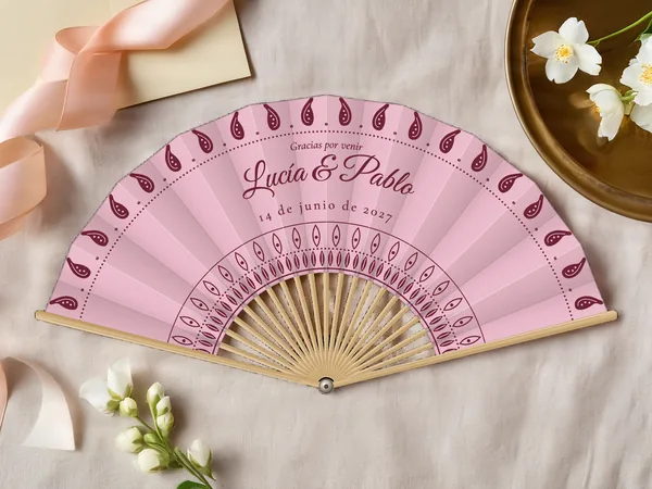 Abanico de boda personalizado «Cachemir», tela rosa empolvado e impresión en burdeos, sobre una mesa de boda