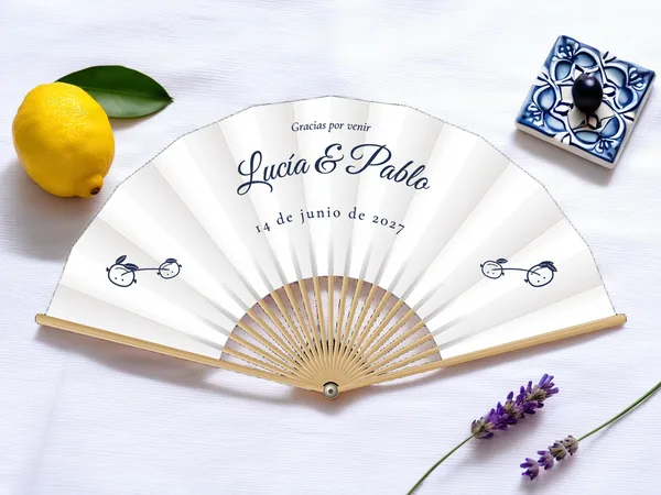 Abanico de boda personalizado «Limonero», tela blanco e impresión en azul marino, sobre una mesa de boda