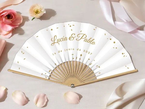 Abanico de boda personalizado «Confeti», tela blanco e impresión en oro, sobre una mesa de boda