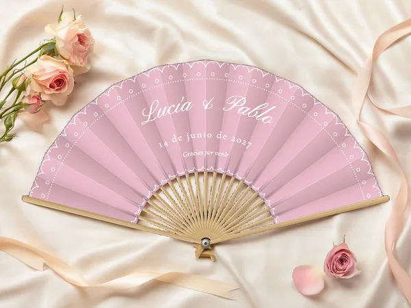 Abanico de boda personalizado «Encaje», tela rosa empolvado e impresión en blanco, sobre una mesa de boda