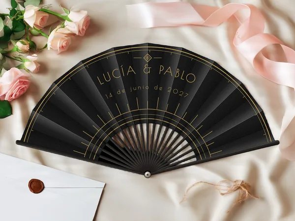 Abanico de boda personalizado «Art déco», tela negro e impresión en oro, sobre una mesa de boda