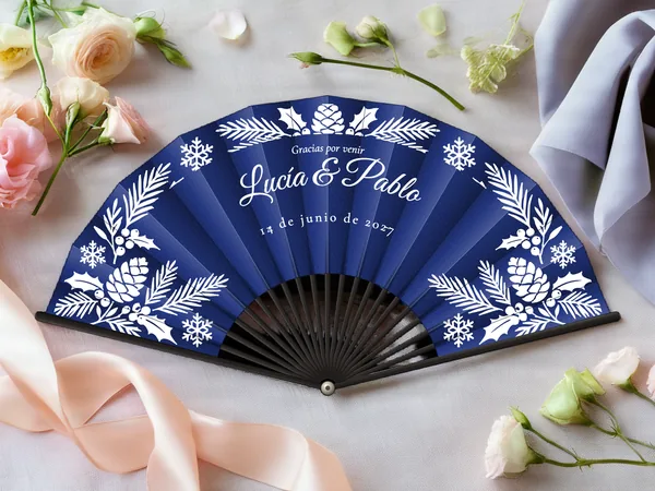 Abanico de boda personalizado «Invierno escarchado», tela azul marino e impresión en blanco, sobre una mesa de boda