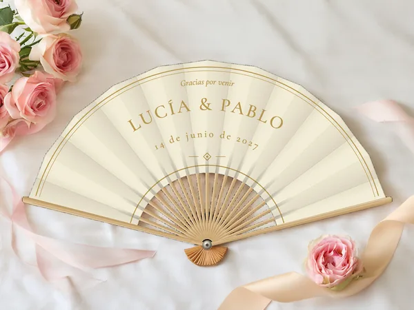 Abanico de boda personalizado «Marfil y oro», tela marfil e impresión en oro, sobre una mesa de boda