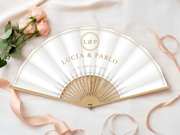 Abanico de boda personalizado «Monograma dorado», tela blanco e impresión en oro, sobre una mesa de boda