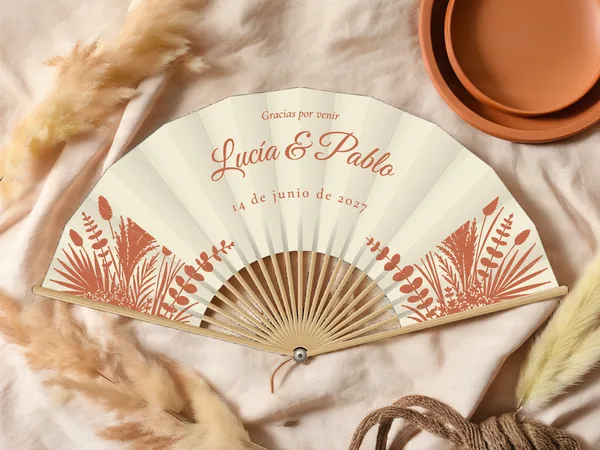 Abanico de boda personalizado «Hierba de la pampa», tela marfil e impresión en terracota, sobre una mesa de boda