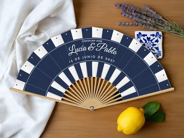 Abanico de boda personalizado «Sombrilla», tela blanco e impresión en azul marino, sobre una mesa de boda