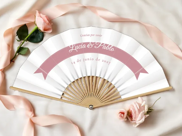 Abanico de boda personalizado «Cinta», tela blanco e impresión en rosa empolvado, sobre una mesa de boda